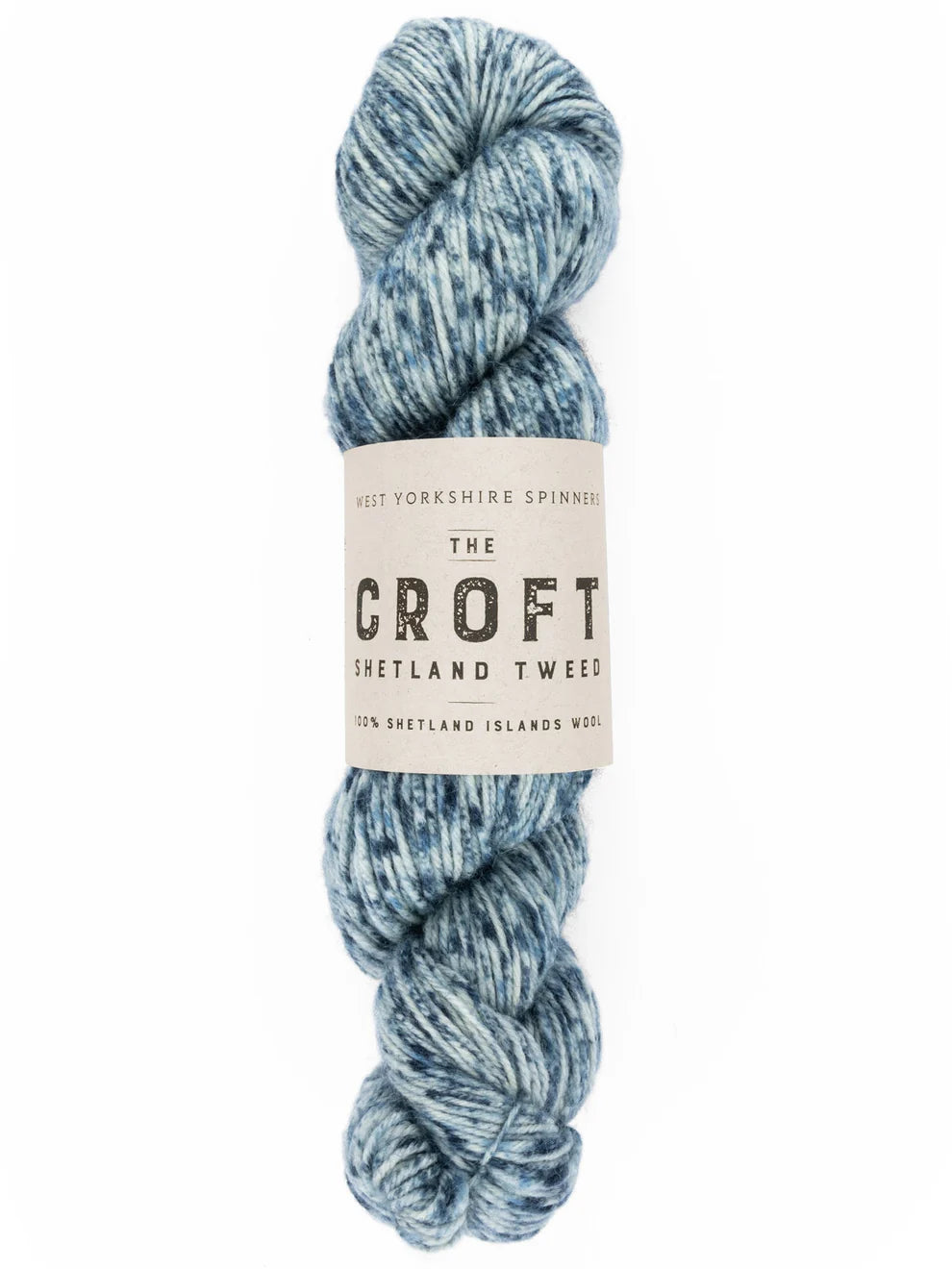 A skein of variegated yarn in shades of dusty blue and navy, wrapped with a paper label that reads 'THE CROFT SHETLAND TWEED'.